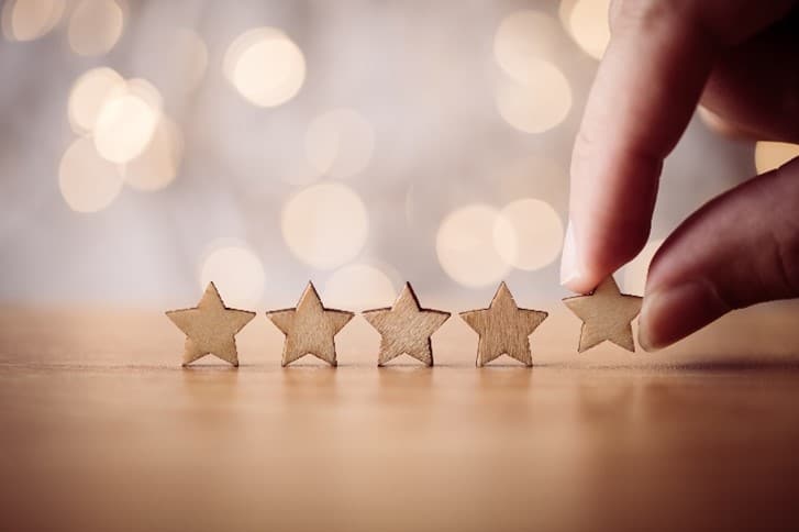 5 wooden stars in a line, one is being picked up by a hand