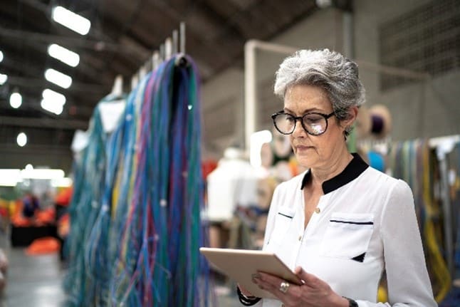 woman wearing glasses with a clipboard in a textile factory